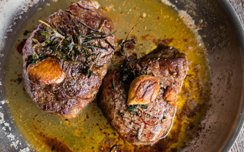 pan-searing bacon-wrapped filet mignon in a cast iron skillet